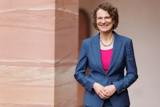 Prof. Dr. Christiane Tietz, Kirchenpräsidentin der EKHN, lächelt in die Kamera. Sie trägt einen blauen Blazer über einem pinkfarbenen Oberteil.